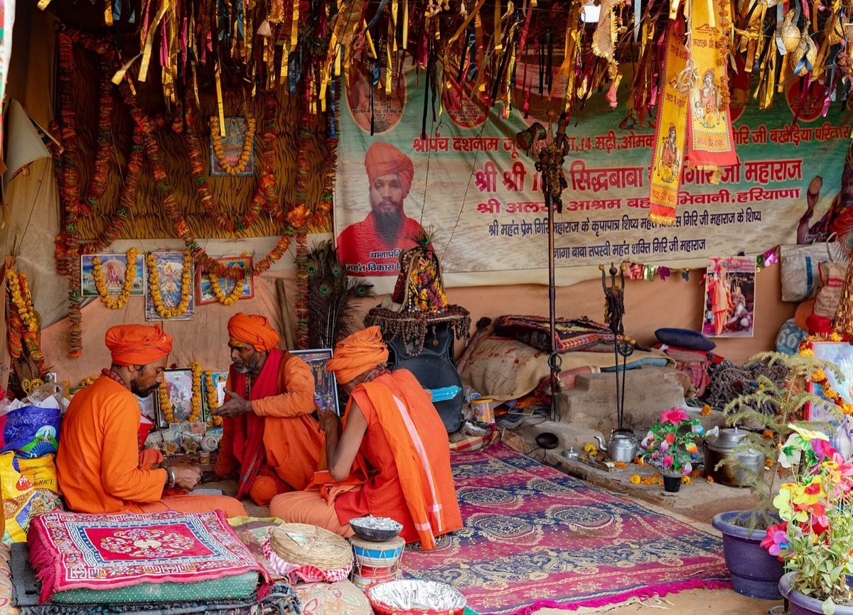 Sadhus seated in a decorated camp shrine of the Juna Akhara at the 2019 Kumbh Mela in Prayagraj