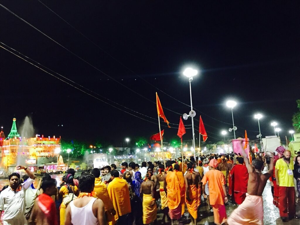 Sadhus in saffron carry tall saffron and red flags through the crowd near the Shipra at night during the 2016 Simhastha Shahi Snan in Ujjain.