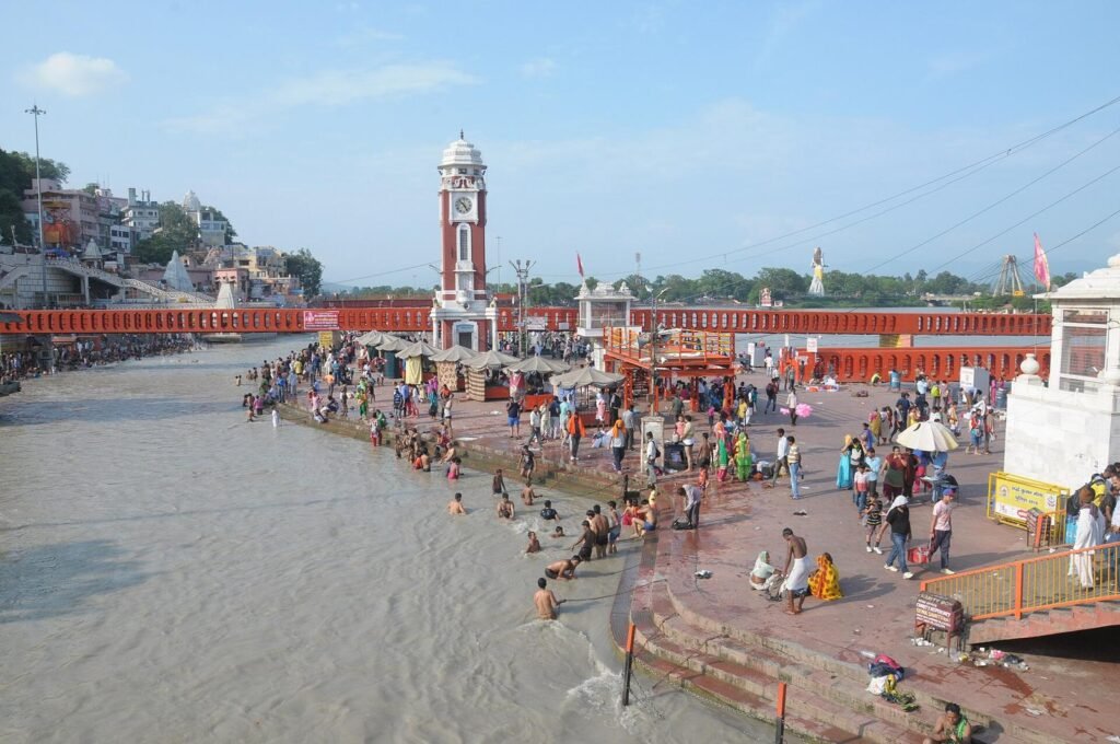 Pilgrims along the ghats and steps of Har Ki Pauri in Haridwar, with the clock tower and the Ganga in front.