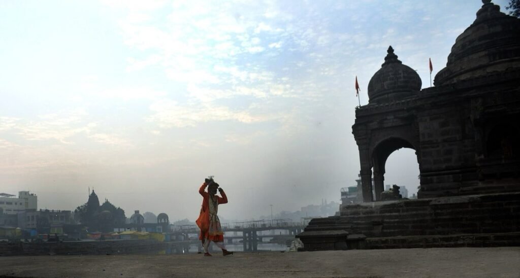 A misty morning at Godha Ghat on the Godavari in Nashik, with a stone temple pavilion on the bank