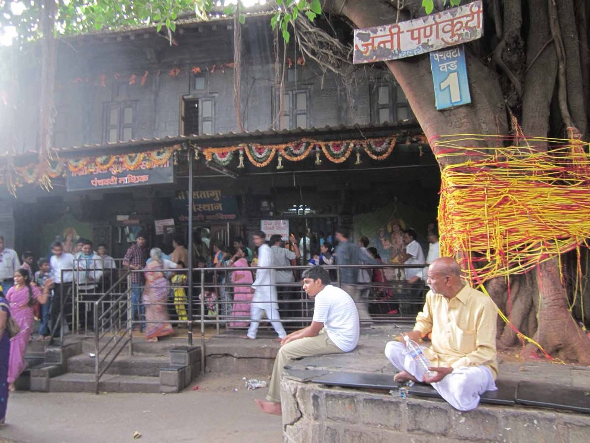 Pilgrims queueing at the entrance to Sita Gufa in Panchavati, Nashik, beside a sacred banyan tree