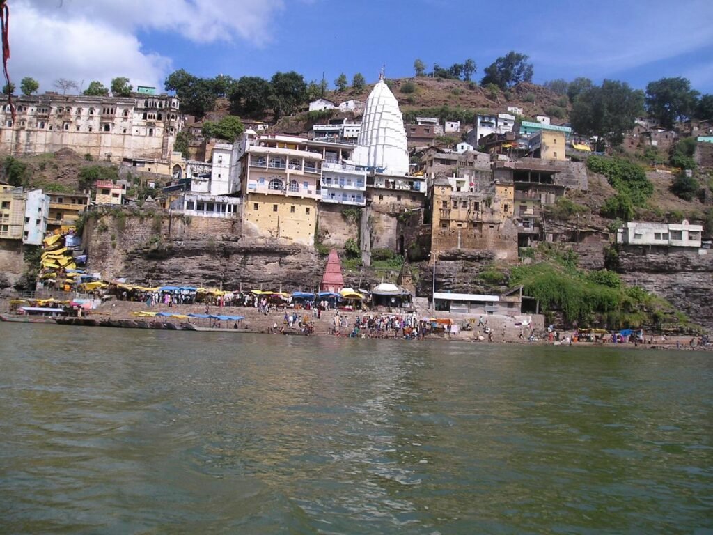 The white shikhara of the Omkareshwar Temple among houses on the island hillside above the Narmada river.