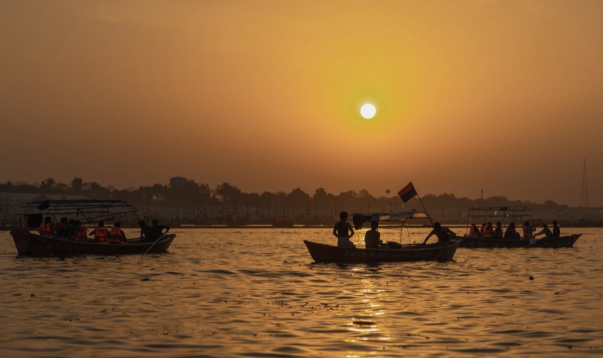 Boats in silhouette on the river at the Sangam with the sun low in the sky, during the 2019 Kumbh Mela