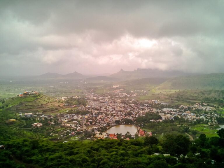 Trimbak town and its green valley under heavy monsoon clouds, with hills all around.