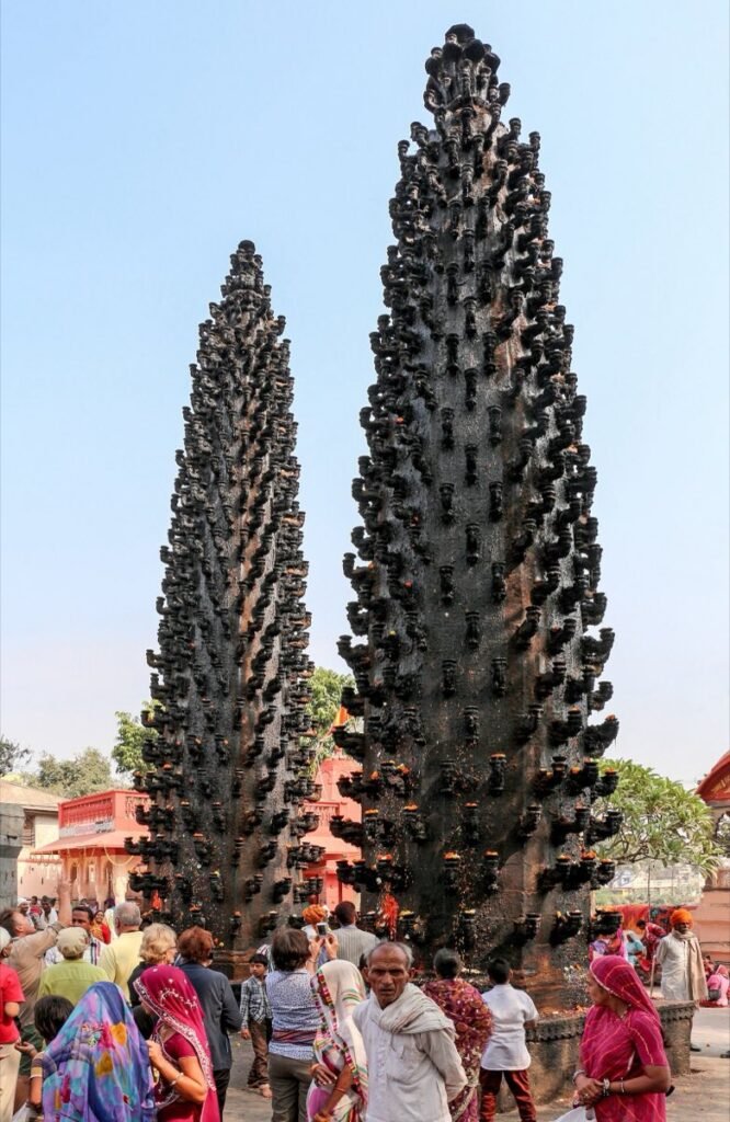 The two tall stone lamp towers at Harsiddhi Temple in Ujjain, with visitors below