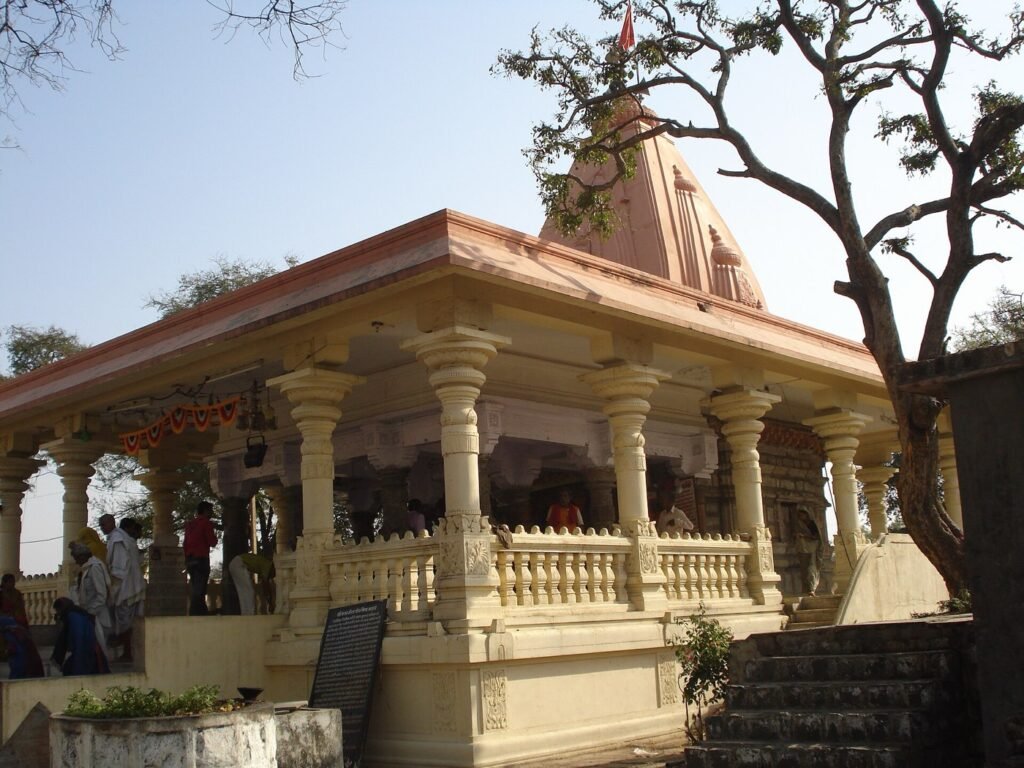 The pillared hall and pale pink shikhara of the Kal Bhairav temple in Ujjain, with devotees on the steps and a flag at the top.